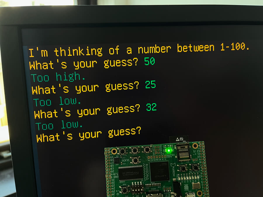 Photograph of ULX3S dev board and monitor showing guessing game.